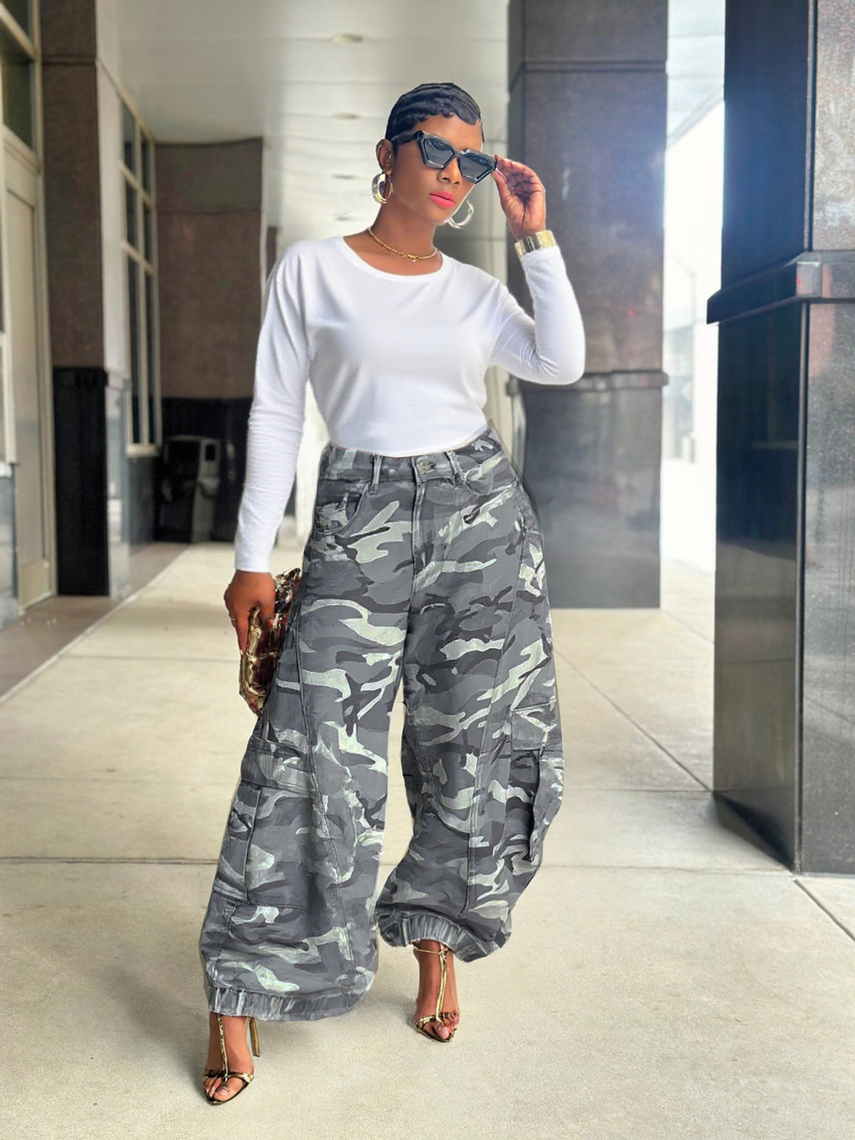 Camo Wide-Leg Cargo Jeans – full-body lifestyle shot, model adjusting sunglasses, styled with white long sleeve top, gold chain, and strappy heels