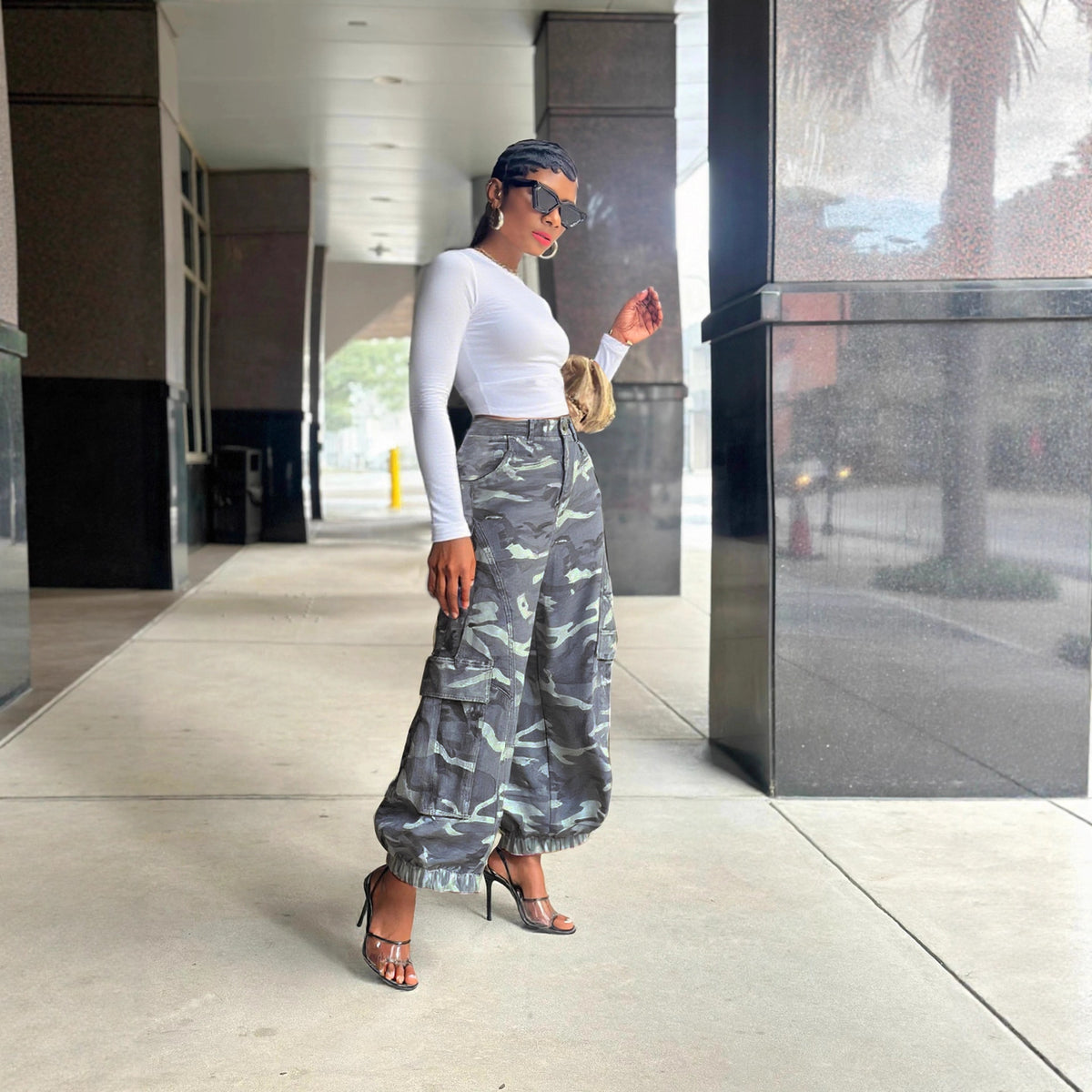 side profile lifestyle shot, styled with white long sleeve crop top, gold mini bag, and strappy heels on urban walkway